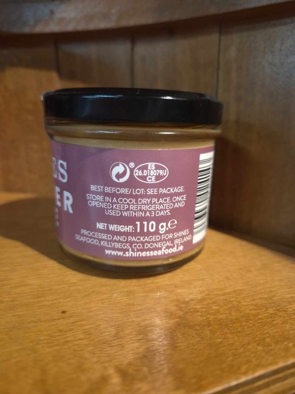 A Shines Tuna PÂTÉ 100g jar, labelled with storage instructions and product details, sits on a wooden shelf. The label lists Shines Seafood, Donegal, Ireland, and the website www.shinessafood.ie.