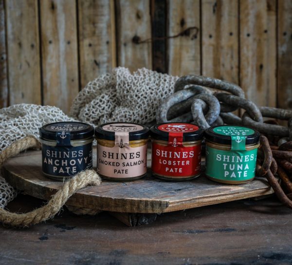The Shines Pâté GIFT BOX (4 x 100g jars) is displayed on a wooden board with rustic fishing nets, ropes, and chains in the background.