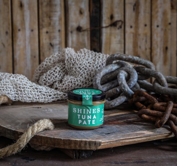 A Shines Pâté GIFT BOX (4 x 100g jars) is displayed on a rustic wooden board with thick chains, rope, and fishing net, set against a wooden plank background.