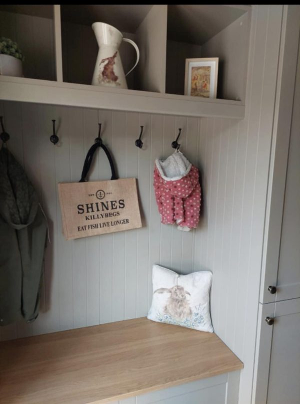 A cosy entrance hall features a wooden bench, hooks with a green coat, the Shines Hessian Bag, and a pink polka dot jacket. A rabbit-print cushion, jug, and framed art complete the decorative look.