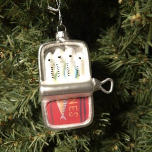 A lemon juicer ornament shaped like the Shines Lemon Juicer hangs on a green Christmas tree.