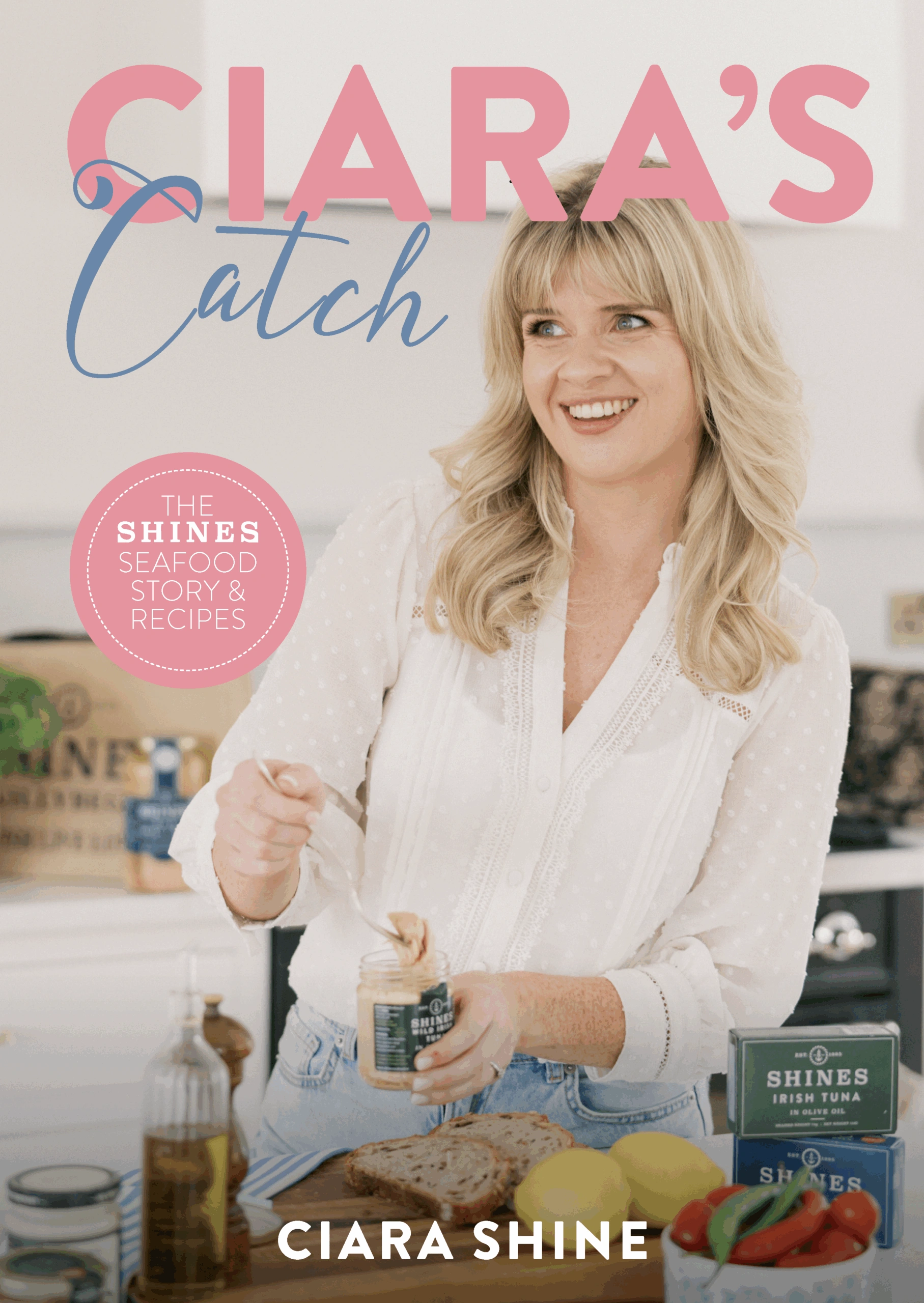 A smiling woman with blonde hair holds a jar of seafood in a bright kitchen. The text on the image reads, "CIARA'S Catch: The Shines Seafood Story & Recipes" and "CIARA SHINE" at the bottom.